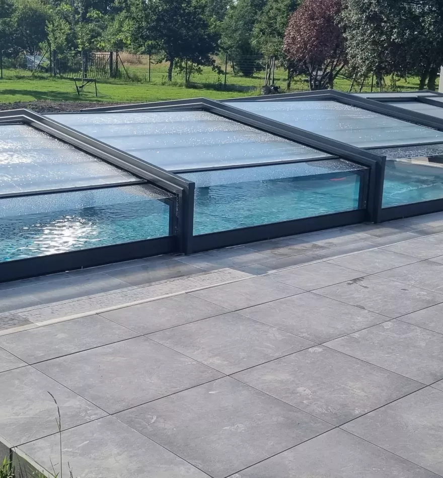 Piscine couverte avec abri, structure noire, jardin paysagé autour